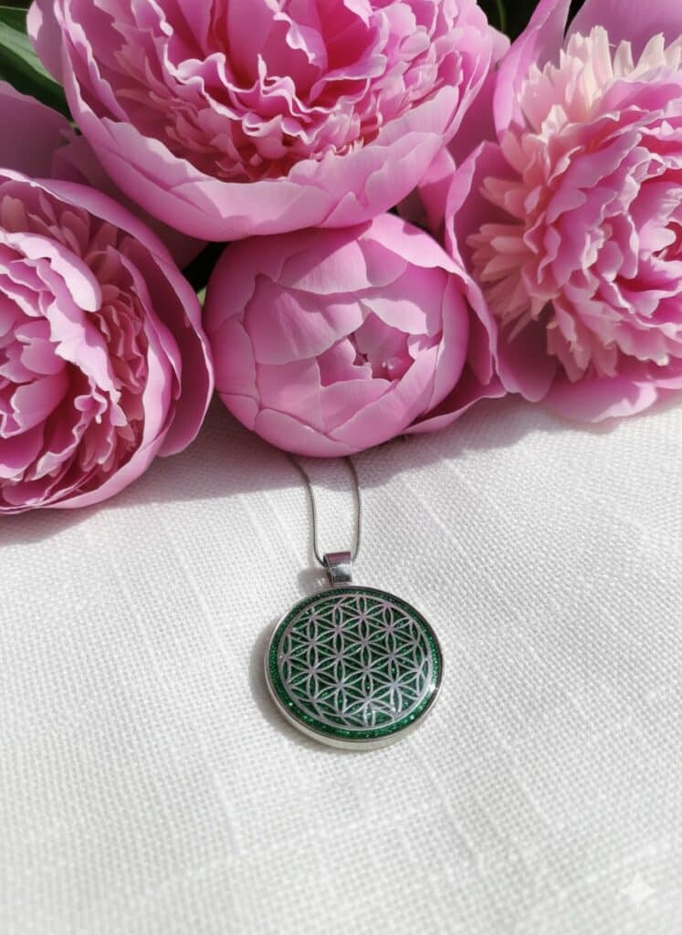 collier Fleur de Vie argentées Ame d'Emeraude fond vert pailleté et d’une Fleur de Vie lumineuse Jewels Spirit vue avec fleurs
