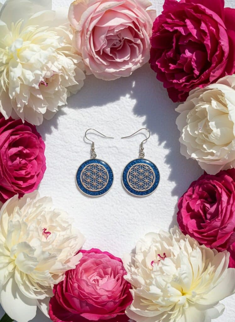 Boucles d’oreilles Fleur de Vie argentées Ciel d’Énergie fond bleu nuit pailleté et d’une Fleur de Vie lumineuse Jewels Spirit vue avec fleurs