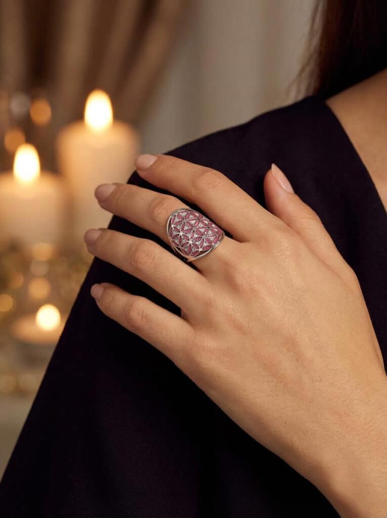 Bague Fleur de Vie Rouge Blanc en acier inoxydable argenté avec fond rouge et blanc pailleté portée sur main