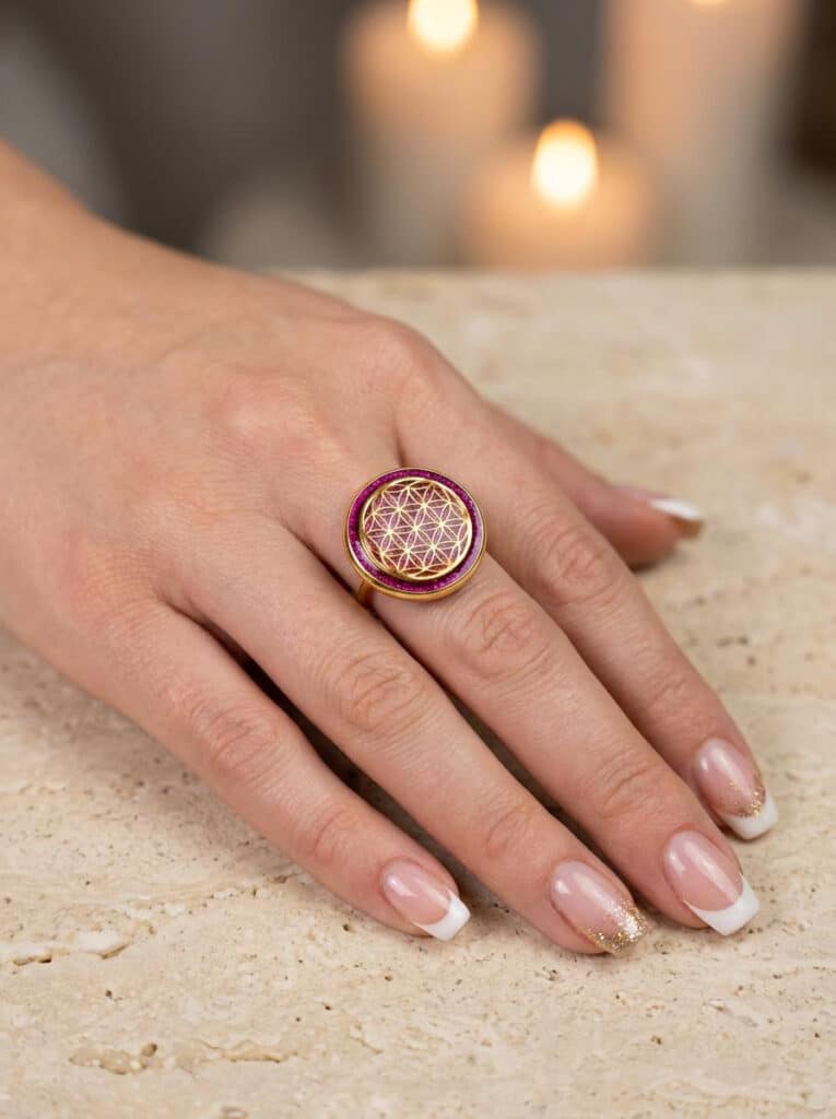 Bague Fleur de Vie fuchsia Éclat Intérieur en acier inoxydable dorée, motif rond avec résine pailletée portée sur une main